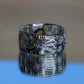 Silver ring with intricate design on a reflective surface